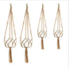 Four handmade macrame plant hangers made of natural brown cotton rope with tassels.