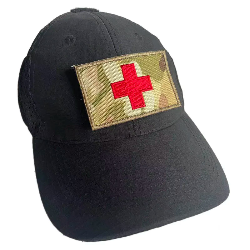 Black baseball cap with a gold camouflage patch featuring a red medical cross.