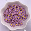 A light purple bowl filled with small, colorful 3D resin flower gems for crafts and DIY projects