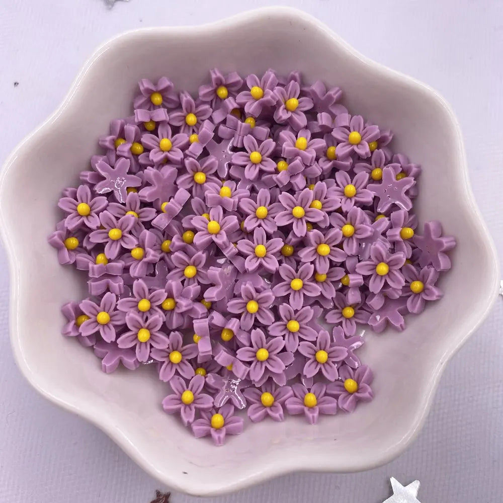 A light purple bowl filled with small, colorful 3D resin flower gems for crafts and DIY projects