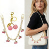 A woman models a white pouch with a gold chain featuring pink glass cherry charms.