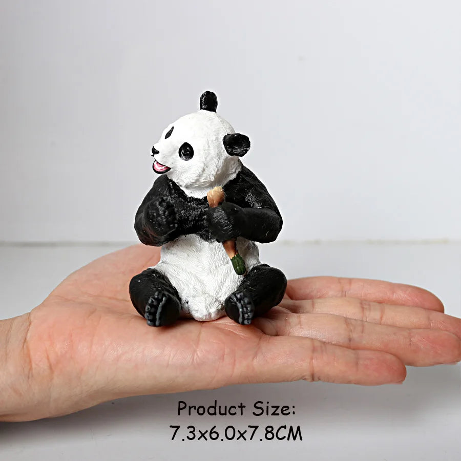 A realistic panda figurine with black and white fur is held in a person's hand.
