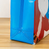 A close-up of a festive blue and red gift bag with handles, showing the textured fabric and design details.