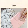 A hand holds a pink portable folding HD makeup mirror with a glitter finish against a light gray patterned fabric.
