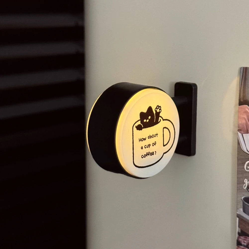 A black magnetic fridge decor featuring a soft glow light shaped like a cup of coffee with a cat face.