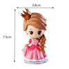 A figurine of a princess with brown hair, a gold crown, and a pink dress, standing on a clear base.