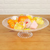 A clear acrylic serving dish filled with various colorful fruit pieces and desserts for entertaining.