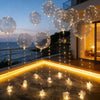A string of glowing LED illuminated party balloons hanging over a wooden deck at dusk.