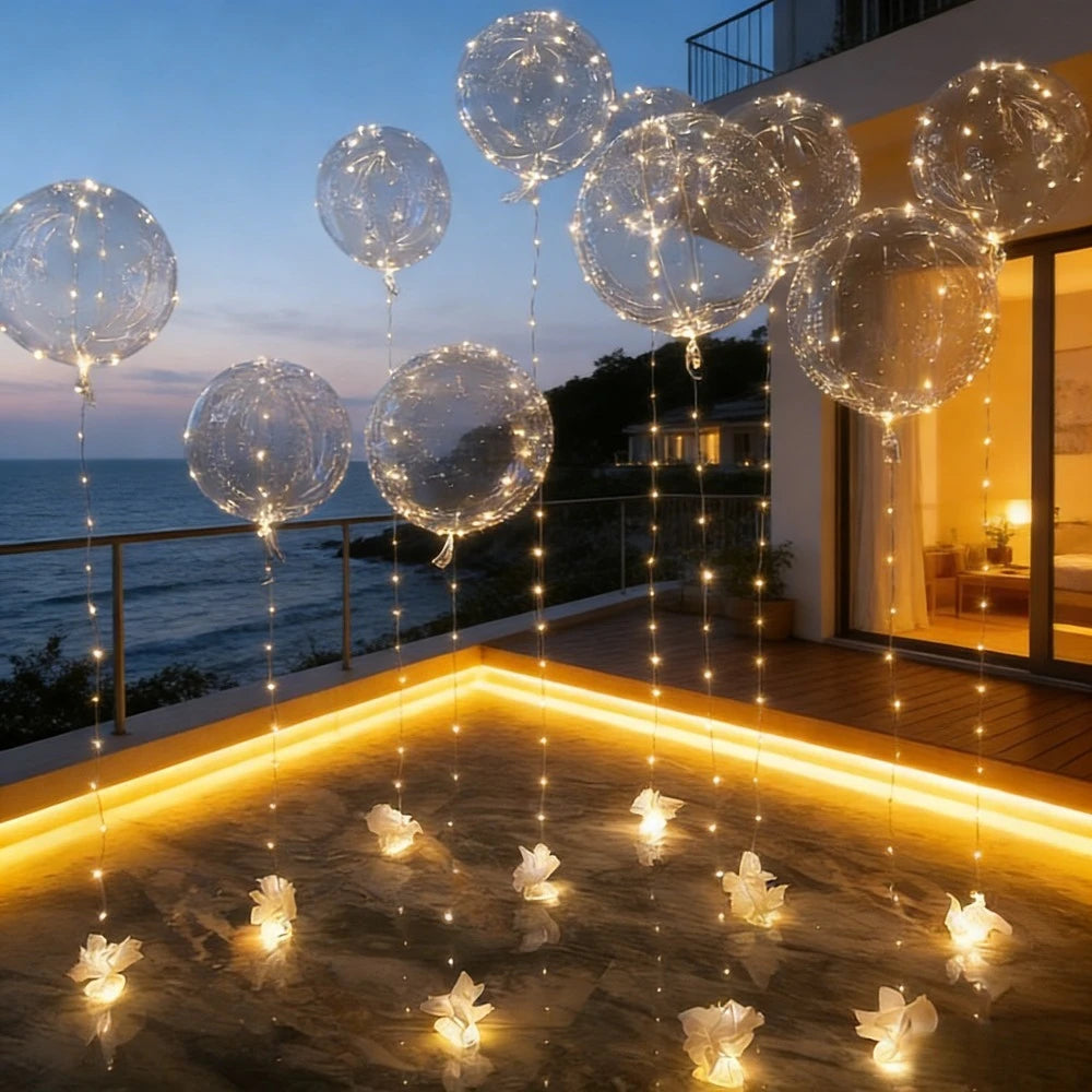 A string of glowing LED illuminated party balloons hanging over a wooden deck at dusk.