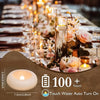 Gros plan d'un photophore en verre avec une bougie LED flottante et un arrangement de roses sur une table à manger.