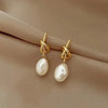 Elegant gold bean spliced pearl drop earrings displayed on a neutral fabric background.
