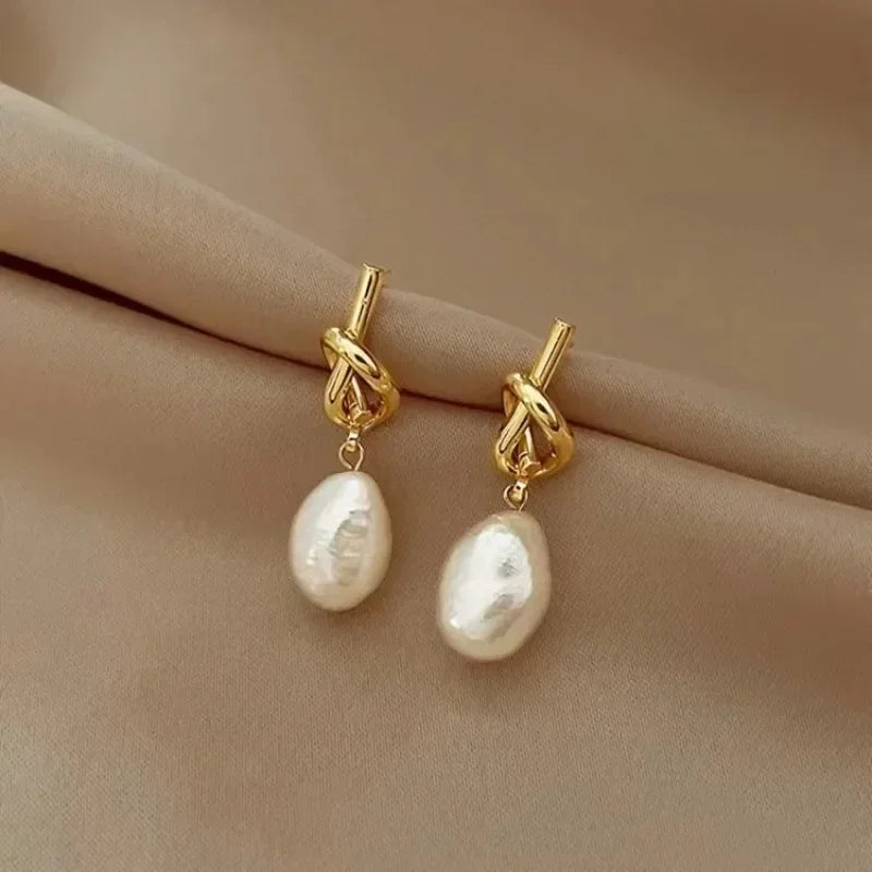 Elegant gold bean spliced pearl drop earrings displayed on a neutral fabric background.