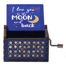 A wooden music box with a lid engraved 'I love you to the moon and back' featuring gold stars and a crescent moon.