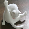 Figura de gato impresa en 3D blanca con lengua rosa asomando, vista de perfil.