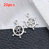 A pair of silver vintage ship anchor charms for jewelry making displayed on a dark surface.