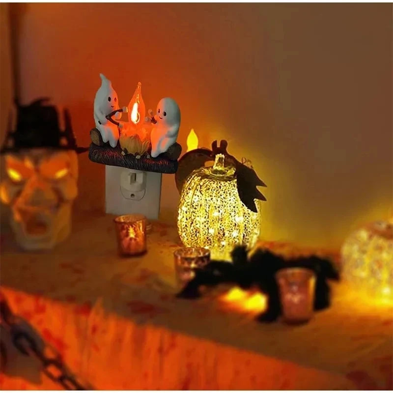A ghost bonfire flickering night light featuring two white ghost figures and warm yellow light on a table.