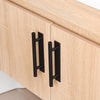 Two black self-adhesive cabinet handles installed on a light wood wardrobe door.