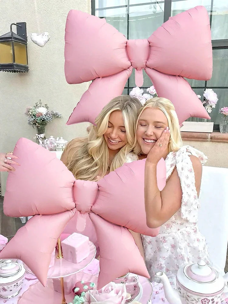 A set of pink balloon banners shaped like bows and flowers for a princess birthday theme.