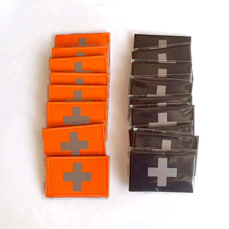 A set of orange and black reflective medical cross tactical morale patches arranged in rows.