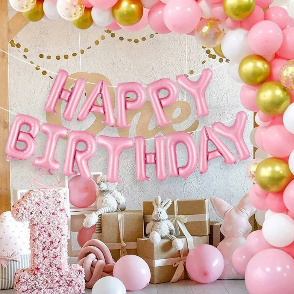 A pink and gold balloon arch decoration featuring foil letter balloons and stuffed animals for a birthday party.