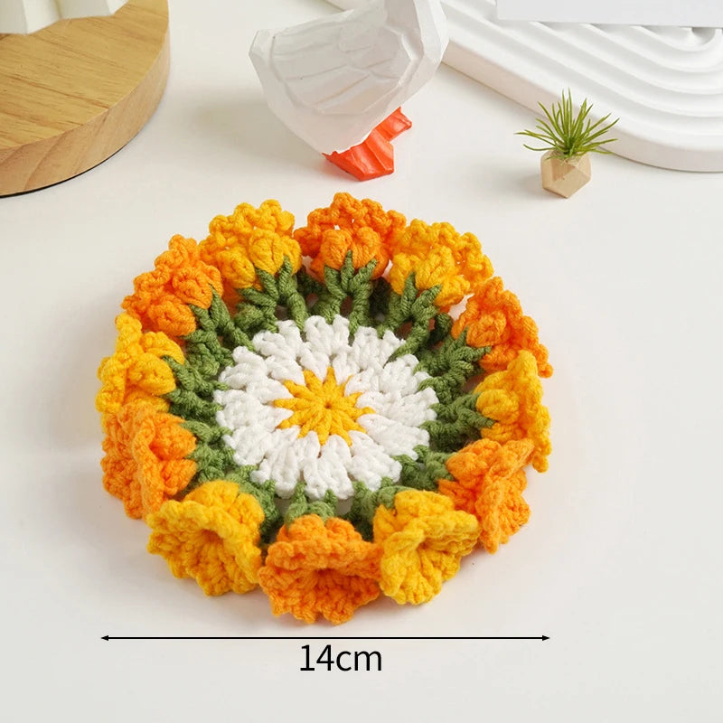 Hand-crocheted orange and white rose flower coasters displayed on a white surface.