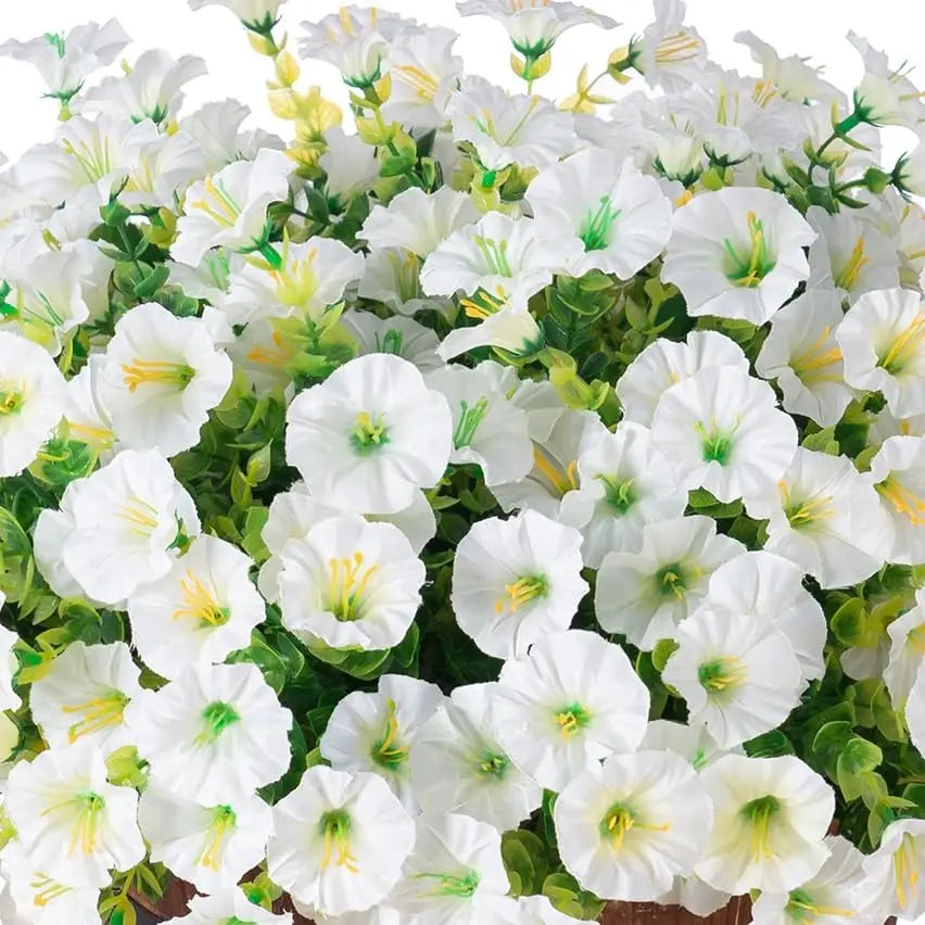 A close-up of white and yellow artificial silk flowers blooming on green foliage for outdoor decor.