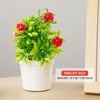 A potted artificial bonsai tree with bright red flowers and green leaves on a light background.