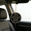 A round leather tag with gold thread hanging from a rearview mirror, featuring Arabic and English text.
