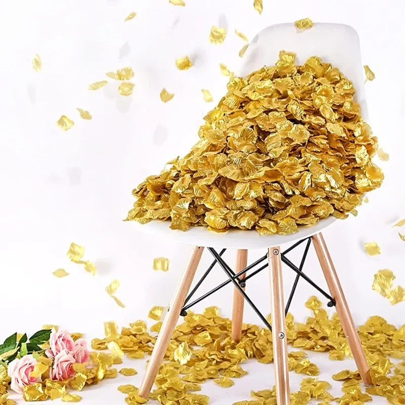 A white ceramic chair holds a pile of gold silk rose petals scattered on a white surface.