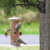 Vintage iron wall hooks with a metal feeder holding a bird in a garden setting