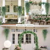 Three lifelike faux eucalyptus hanging plants decorating a wedding backdrop