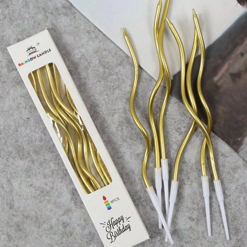A set of six gold curved decorative birthday candles displayed on a white cardboard box.