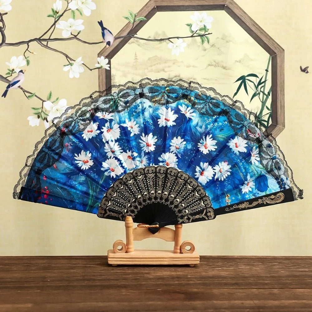 A blue and white floral Spanish style folding lace trim handheld fan displayed against a light background.