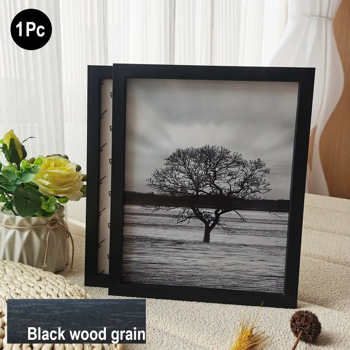 A black wooden photo frame displaying a grayscale silhouette of a tree against a misty landscape.