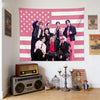 A pink American flag tapestry featuring Kpop idols standing in front of the flag.