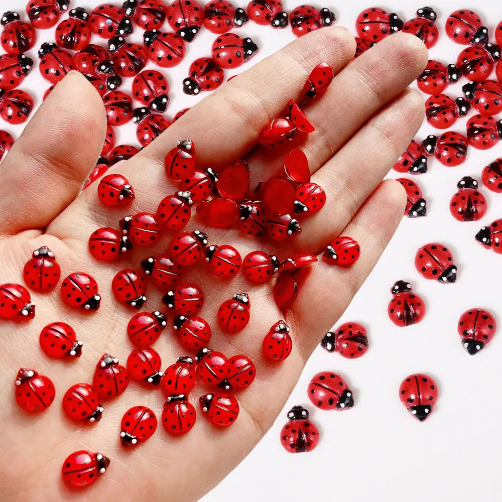 A hand holds a large quantity of red ladybug resin nail art charms.