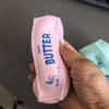 A hand holds a pink butter squeeze toy labeled 4oz salted butter for stress relief.