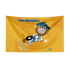 A yellow flag tapestry featuring a cartoon monkey graduate wearing a blue cap and gown, with text acknowledging Kanye West.