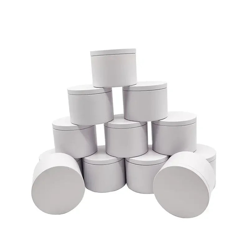 A set of white metal candle tins with lids arranged in a pyramid formation.