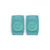 A pair of teal knitted knee pads with a smiling face design.