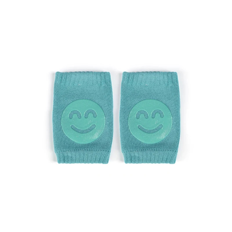 A pair of teal knitted knee pads with a smiling face design.