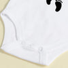 White baby bodysuit with a black footprint design for a newborn announcement.