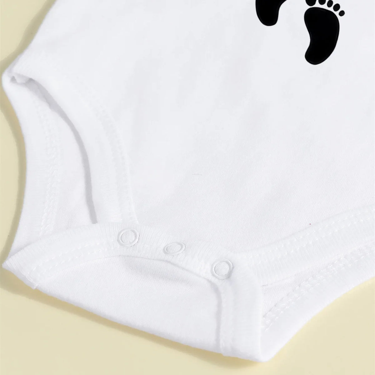 White baby bodysuit with a black footprint design for a newborn announcement.