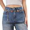A close-up of blue denim jeans featuring a multi-colored crystal waist chain embellishment.