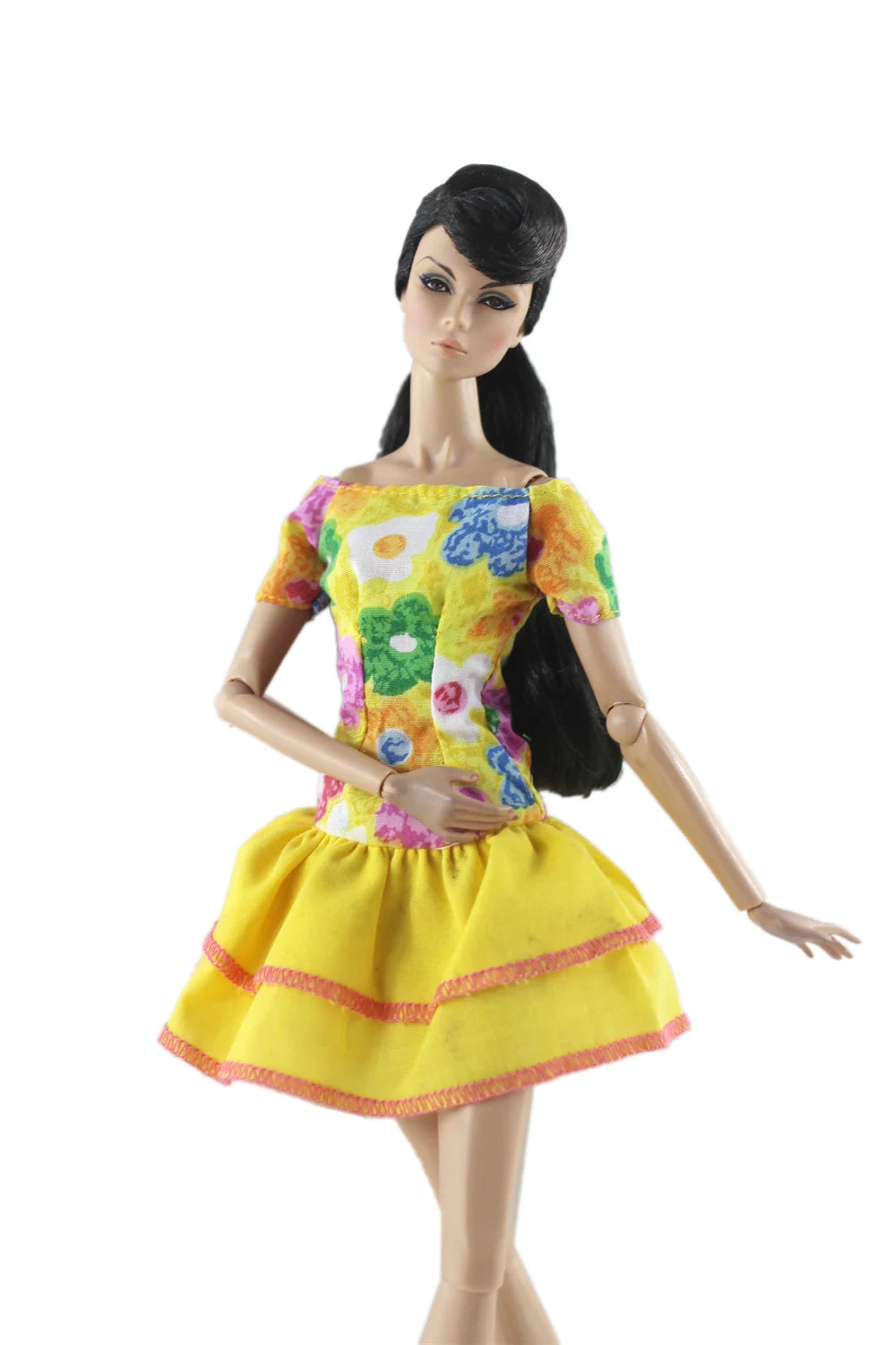 A handmade doll dress gown featuring a yellow bodice with floral patterns and a ruffled yellow skirt.