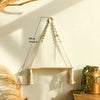 A macrame wood floating wall shelf with a hanging rope is displayed on a light-colored wall.