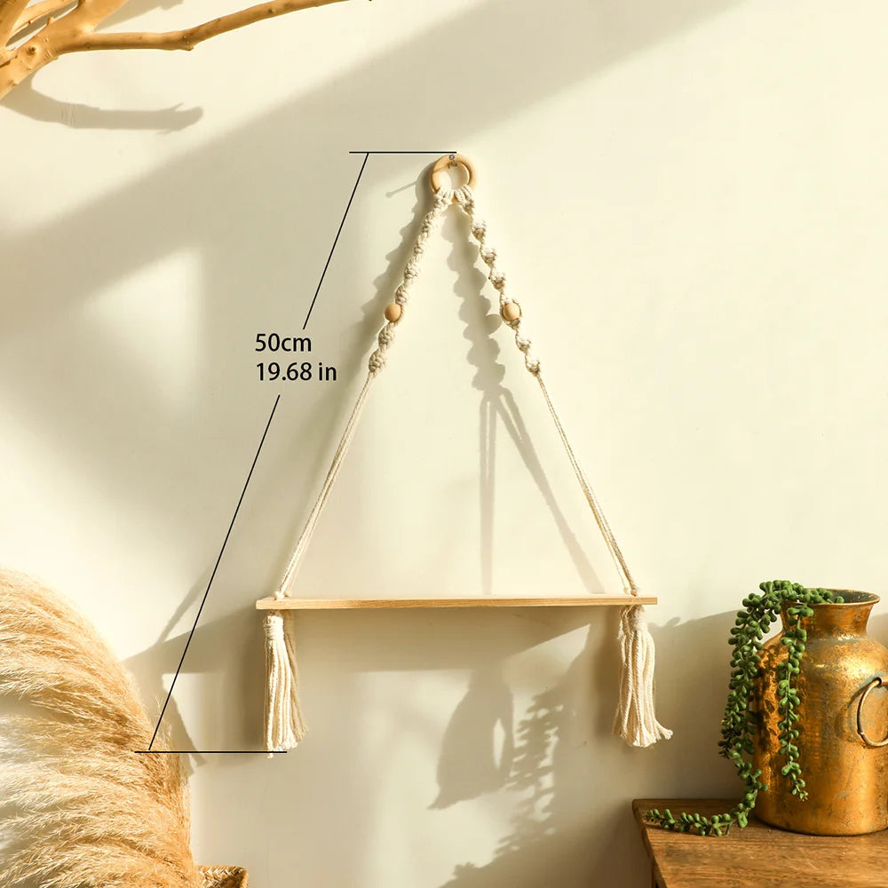 A macrame wood floating wall shelf with a hanging rope is displayed on a light-colored wall.