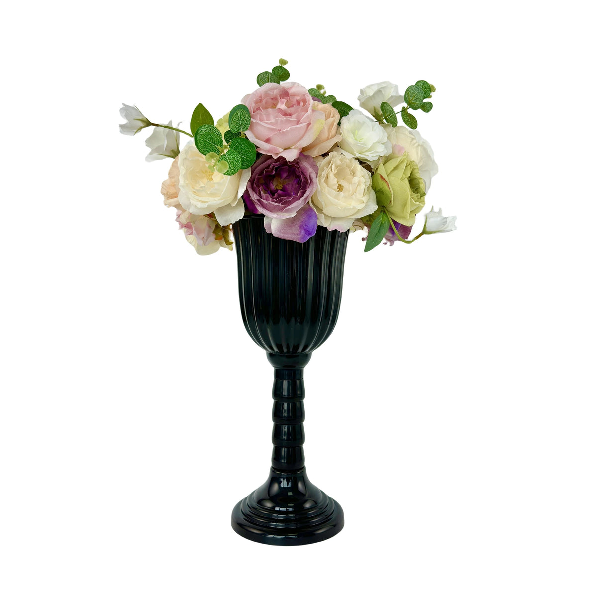 A dark, fluted vase holds a bouquet of pink, cream, and purple roses and greenery.