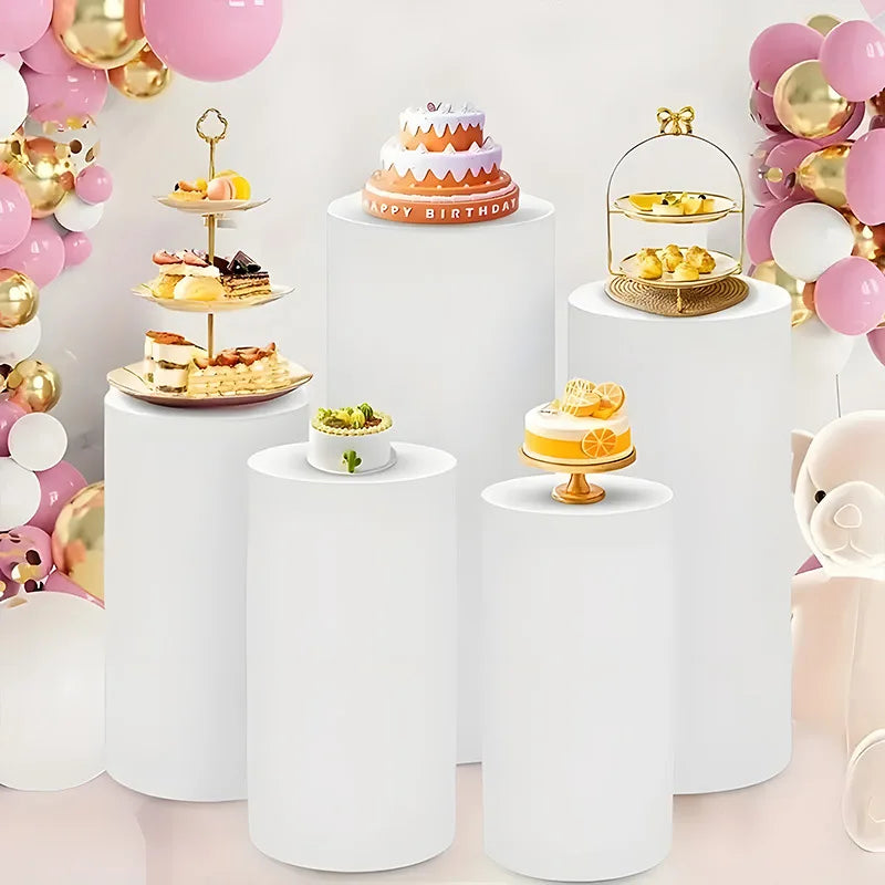 White elastic cylinder stands used to display birthday cakes and party decorations