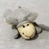 A small, gray and yellow plush animal with large ears and a smiling face.